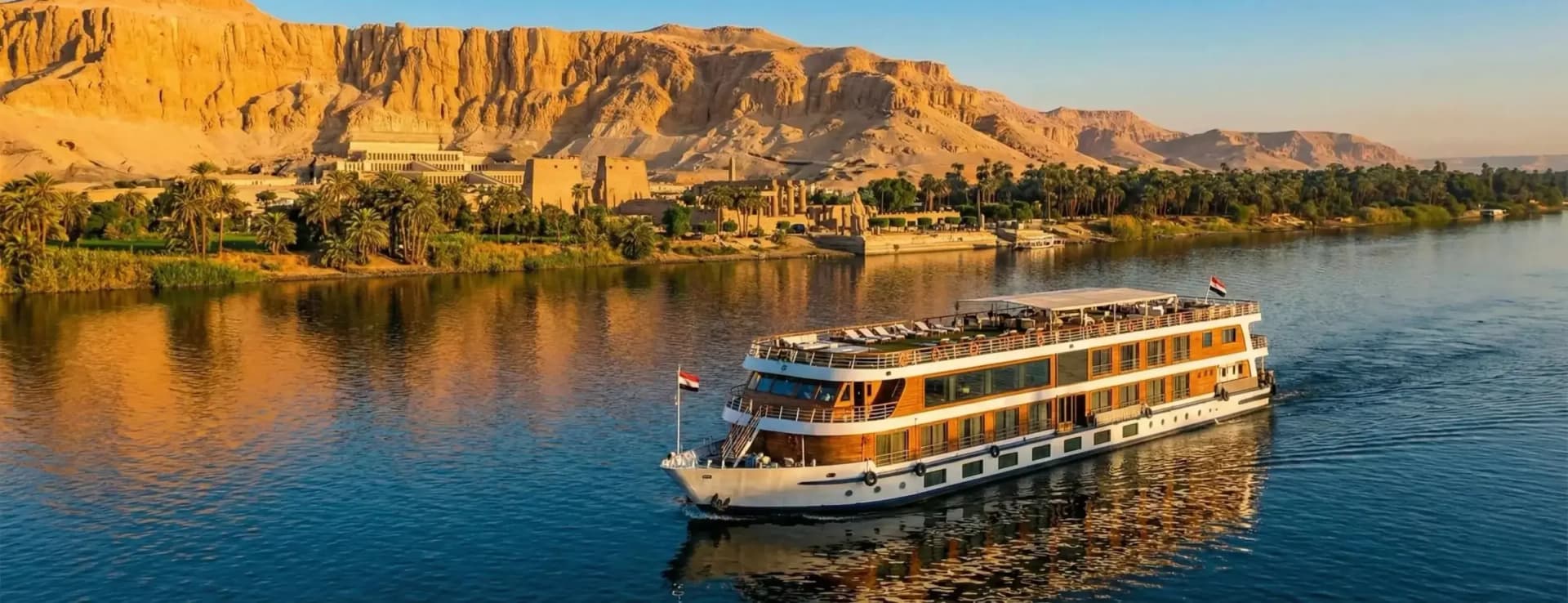 Een nijlcruiseschip op de Nijl bij Luxor, met de tempel van Hatsjepsoet en de rotsen van de westoever erachter