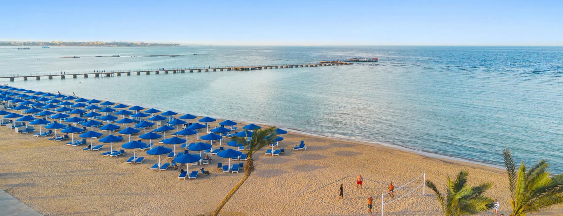 Het strand van Makadi Bay met parasols en de steiger de zee in