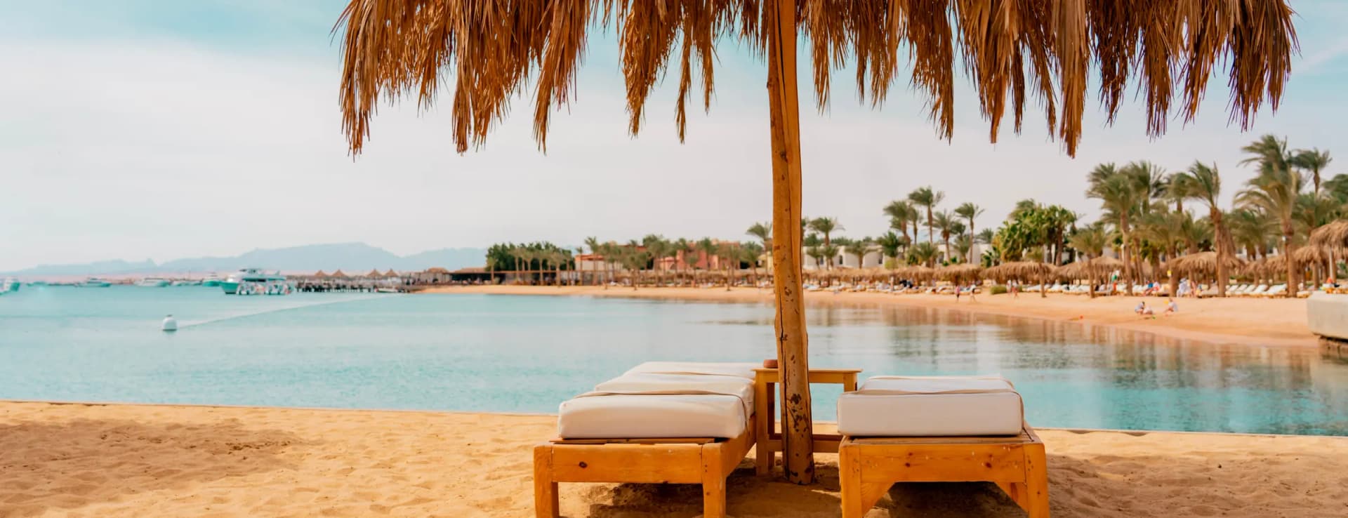 Parasol en twee ligbedden aan een baai van de Rode Zee bij Hurghada